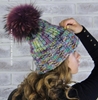 картинка вязаная женская шапка из мериноса с большим помпоном из натурального меха енота, цвет: меланж , помпон сливовый